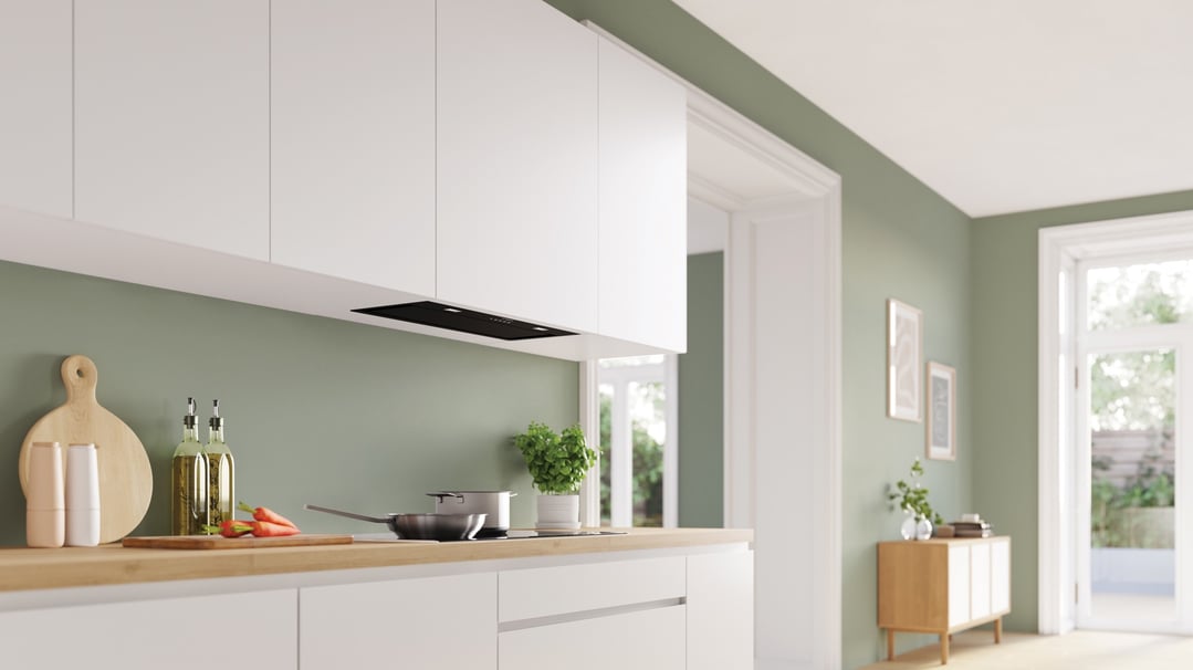 Integrated rangehood in a modern kitchen with white cabinets and green walls