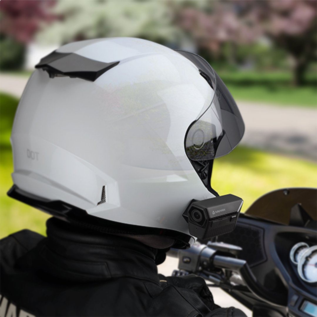 Dash cam mounted on a white motorcycle helmet worn by a person riding a motorcycle