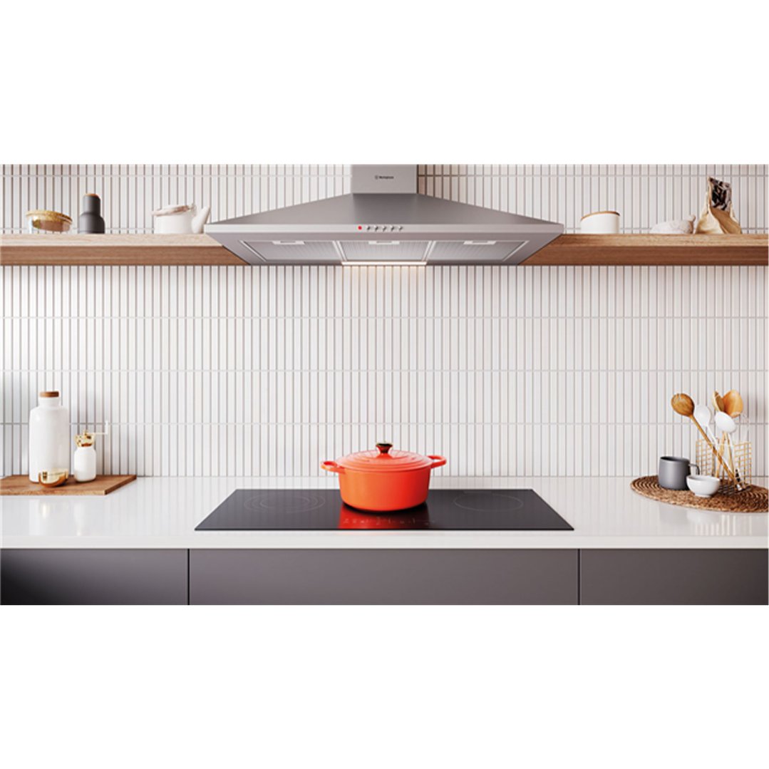 Stainless steel canopy rangehood above an induction cooktop with an orange pot
