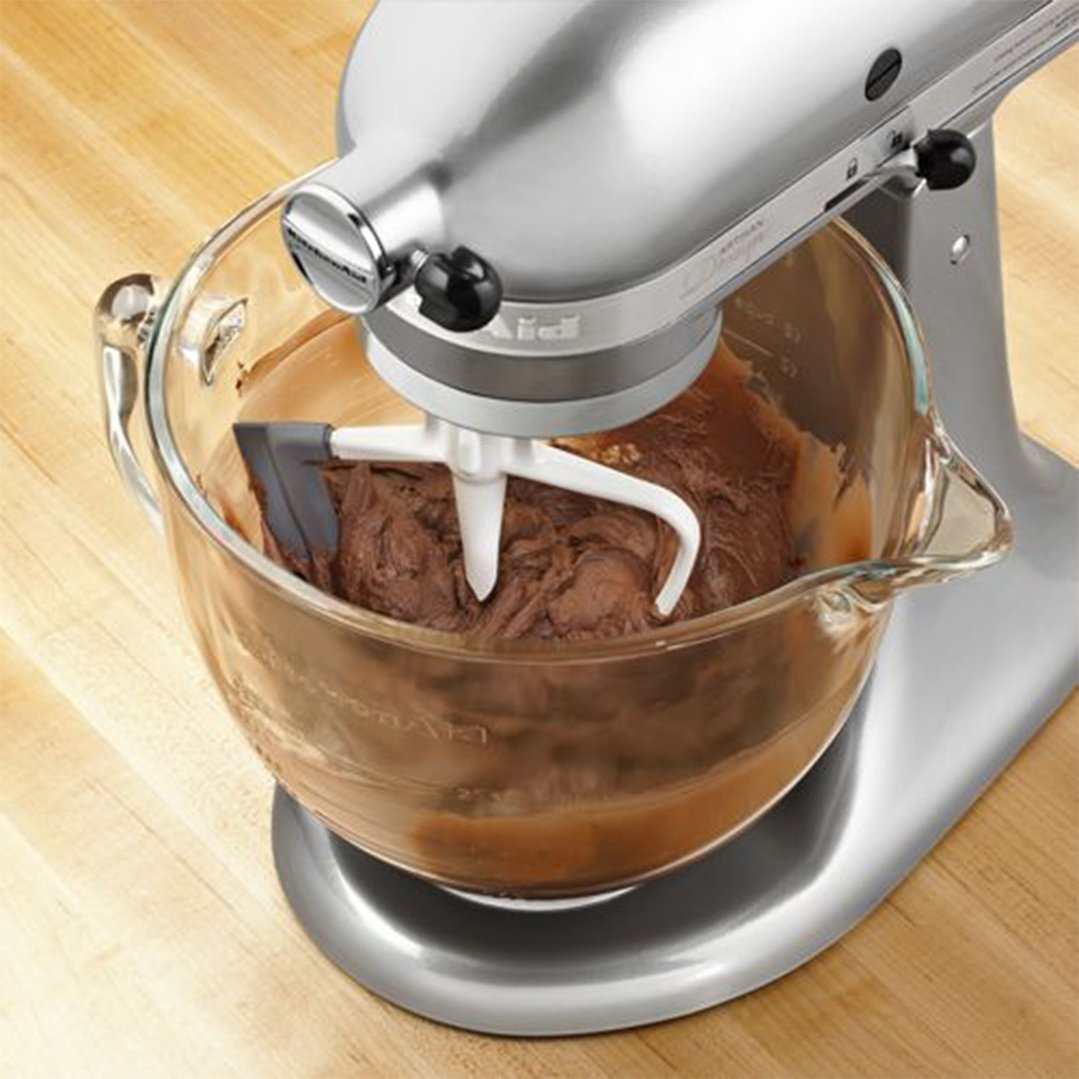 KitchenAid stand mixer with a glass bowl mixing chocolate batter on a wooden surface