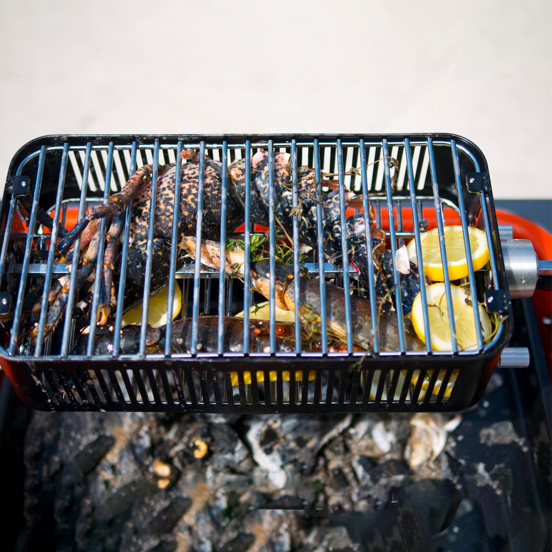 Lobster and lemon cooking in a rotisserie cage over hot coals