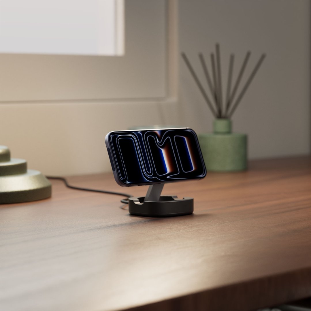 Wireless charger with a phone on a wooden desk next to a lamp