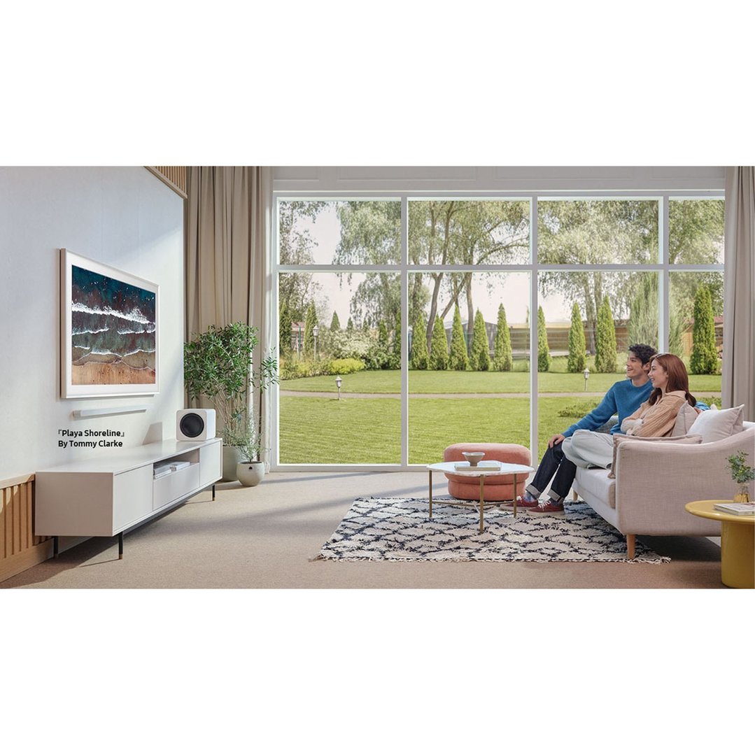 A couple relaxing on a sofa in a living room with a TV on the wall