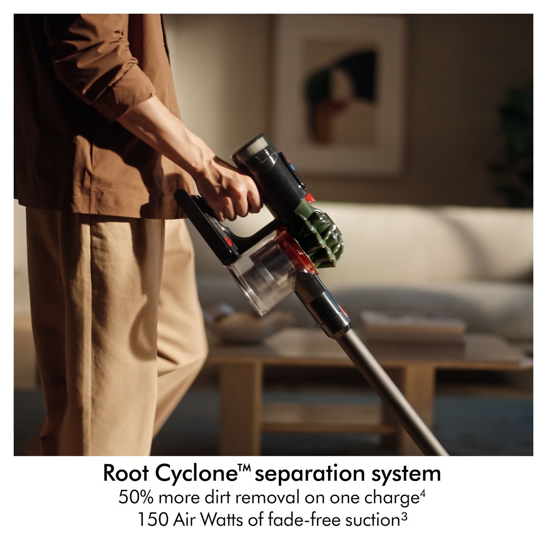 Person holding a Dyson handstick vacuum in a living room setting