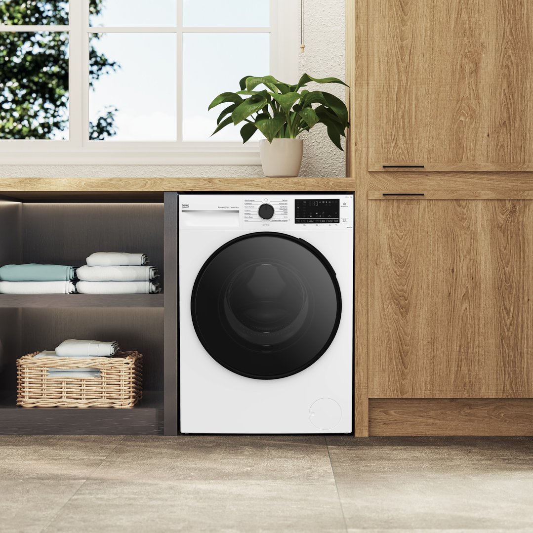 White front load washing machine in a modern laundry room with wooden cabinets