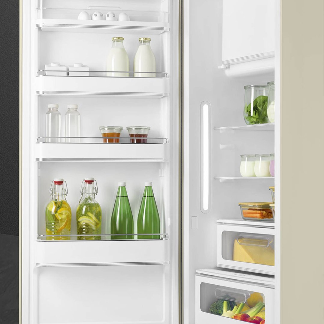 Open cream retro refrigerator filled with various food and drink items