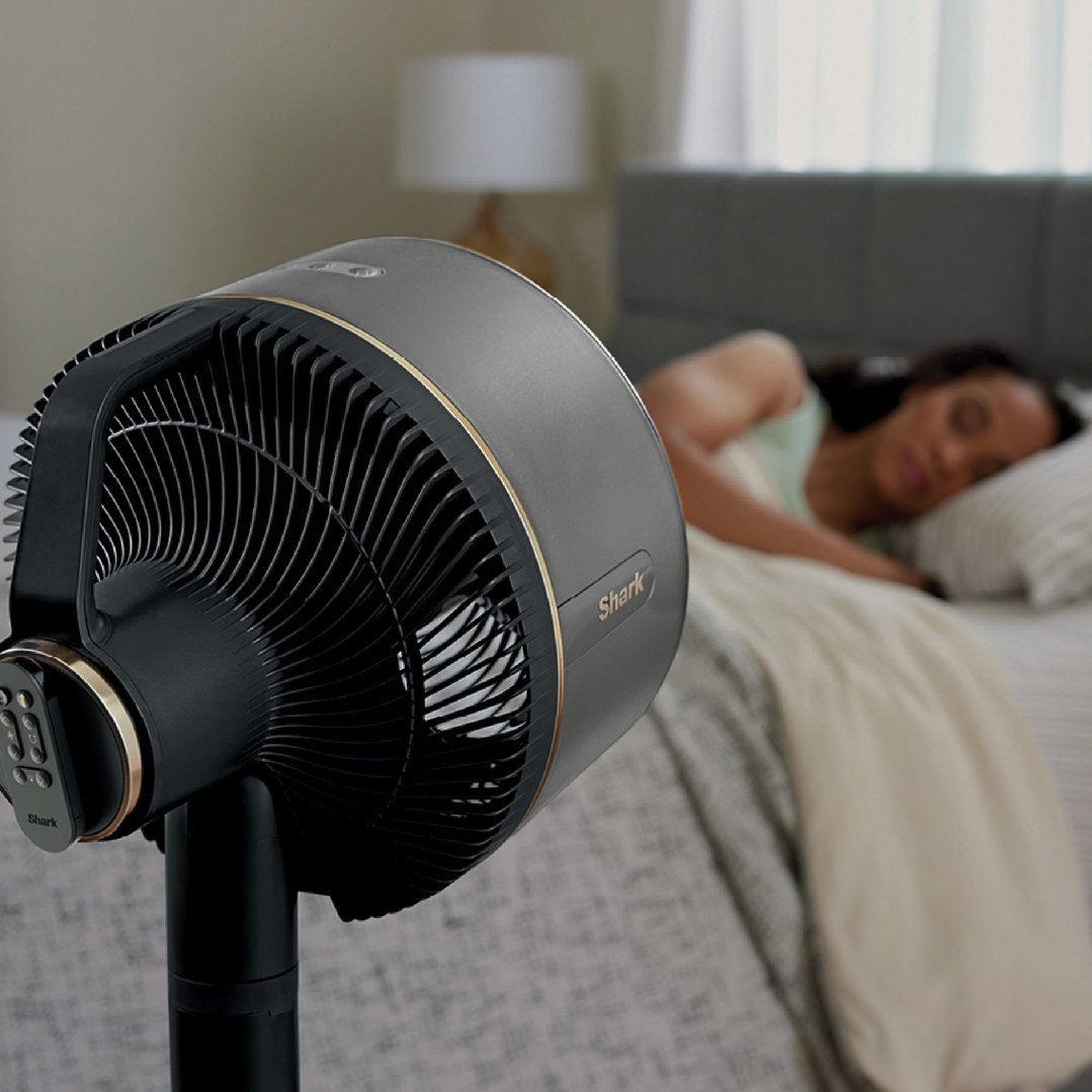 Shark fan on a stand in a bedroom with a person sleeping
