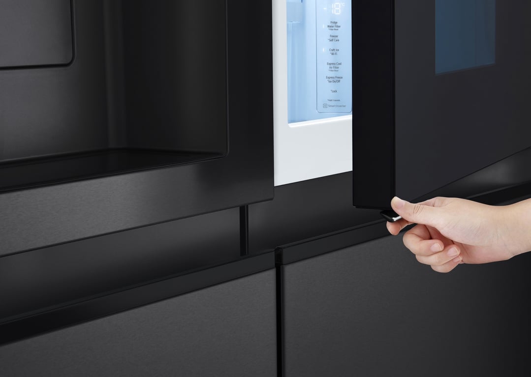 Hand opening the door of a matte black LG side by side fridge