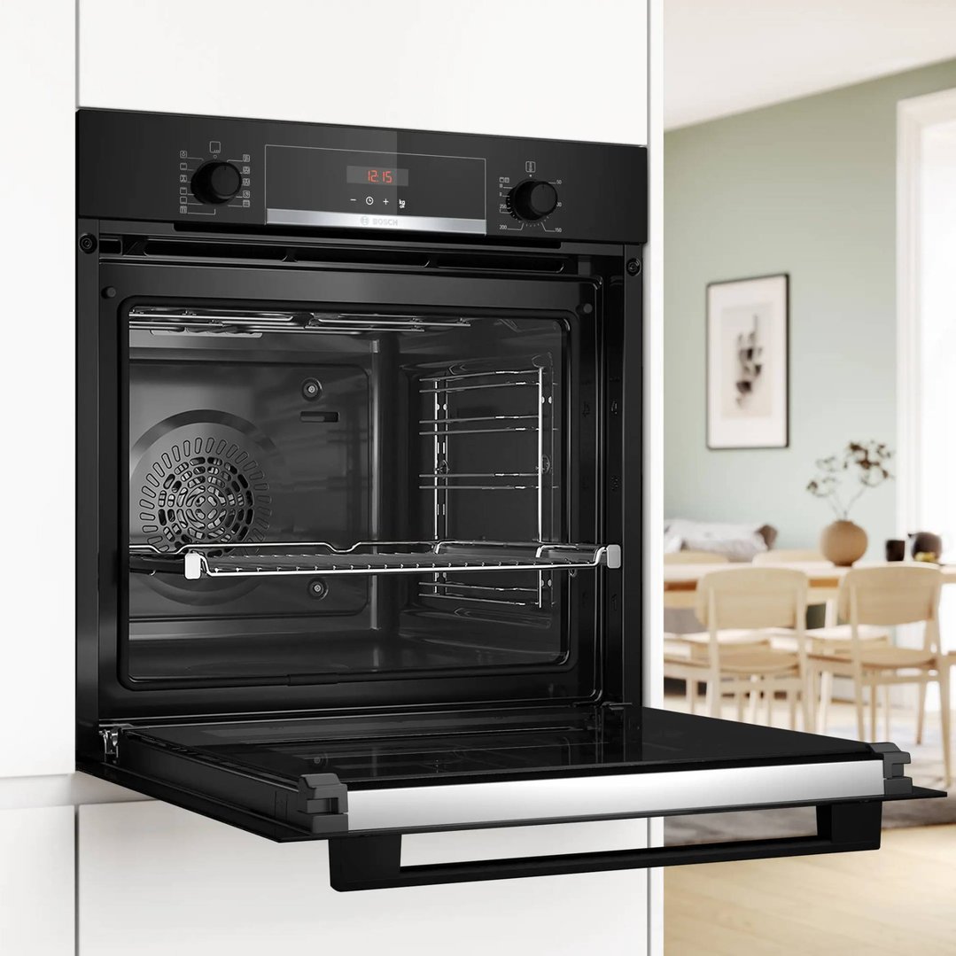 Black built-in oven with door open in a modern kitchen setting