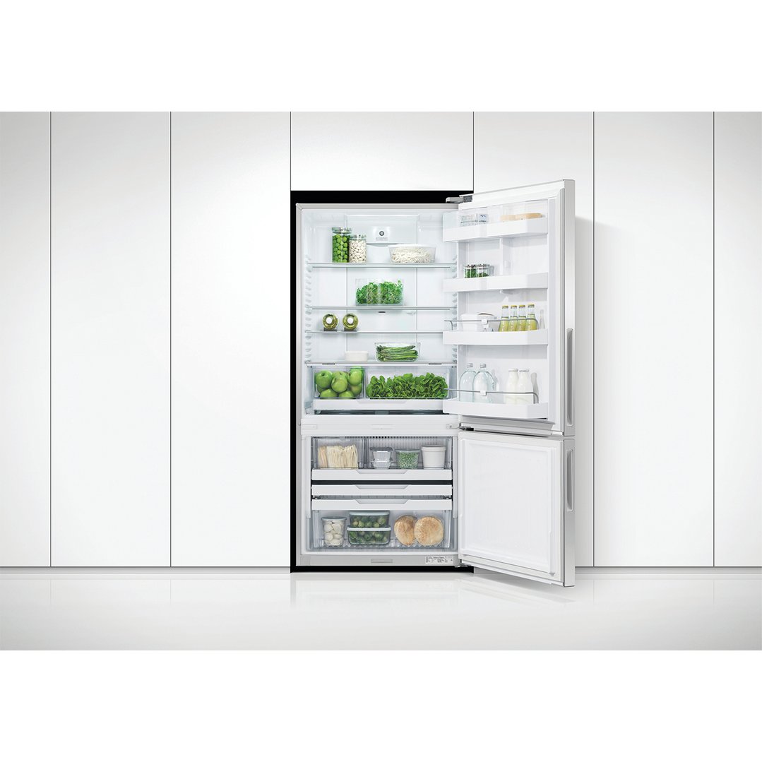 Open refrigerator freezer filled with food, integrated into white kitchen cabinetry