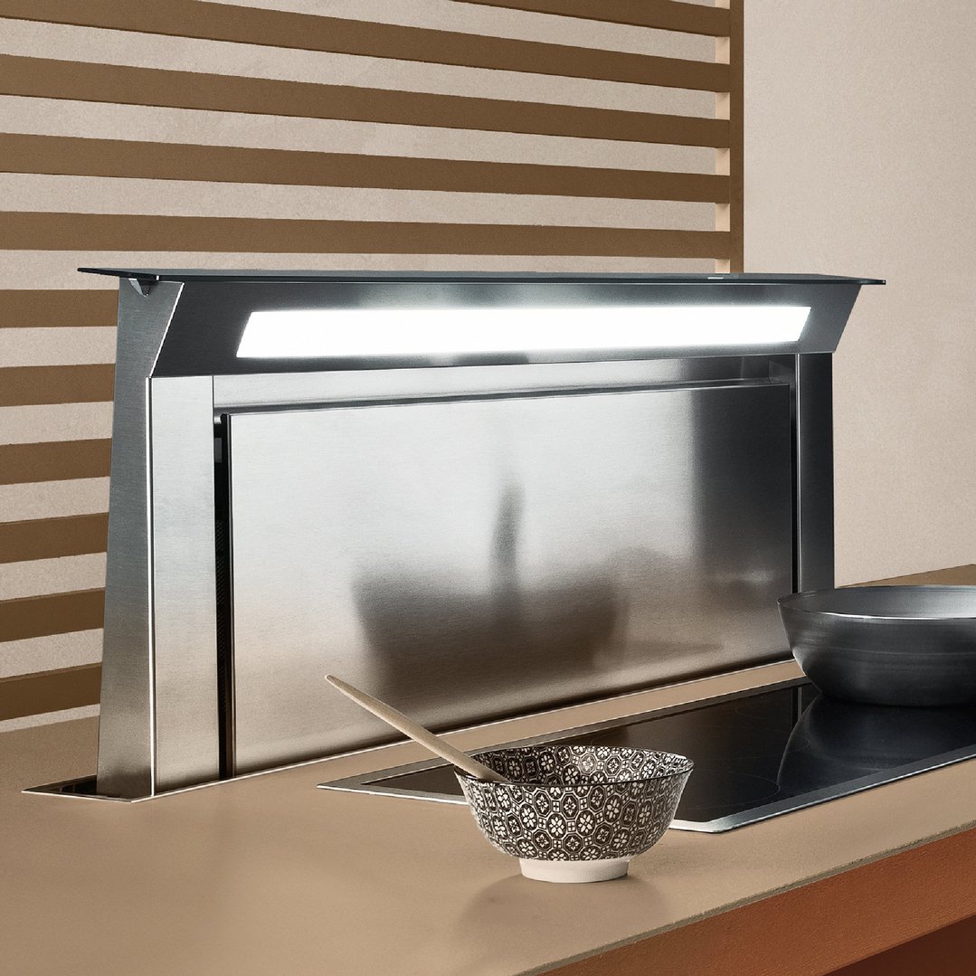Downdraft system with a bowl and pan on a cooktop in a kitchen