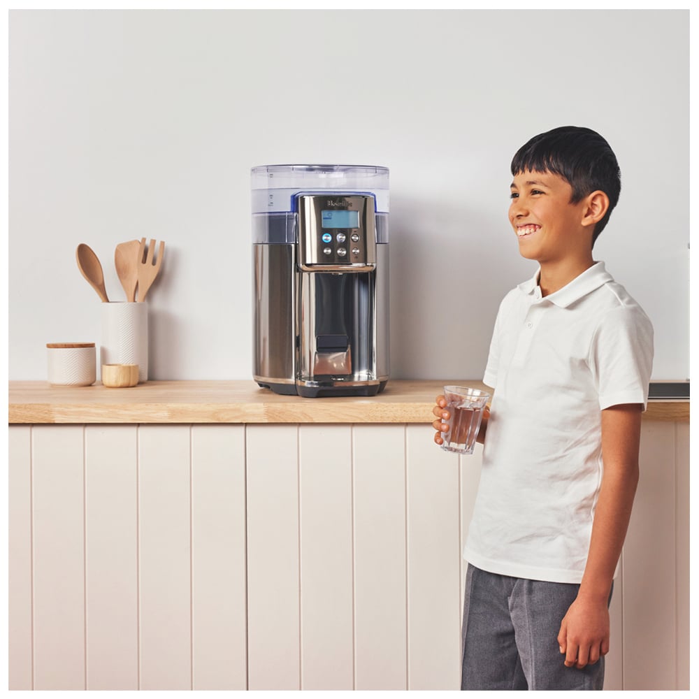 Young boy holding a glass of water next to a Breville AquaStation