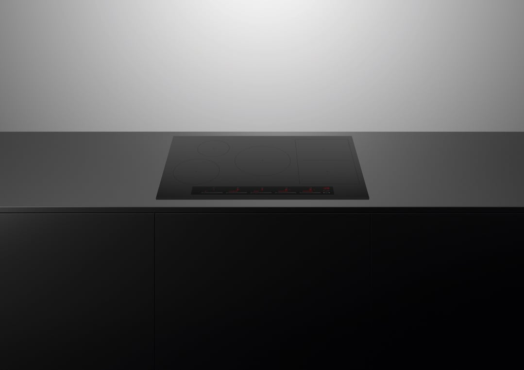 Black induction cooktop built into a dark countertop in a modern kitchen