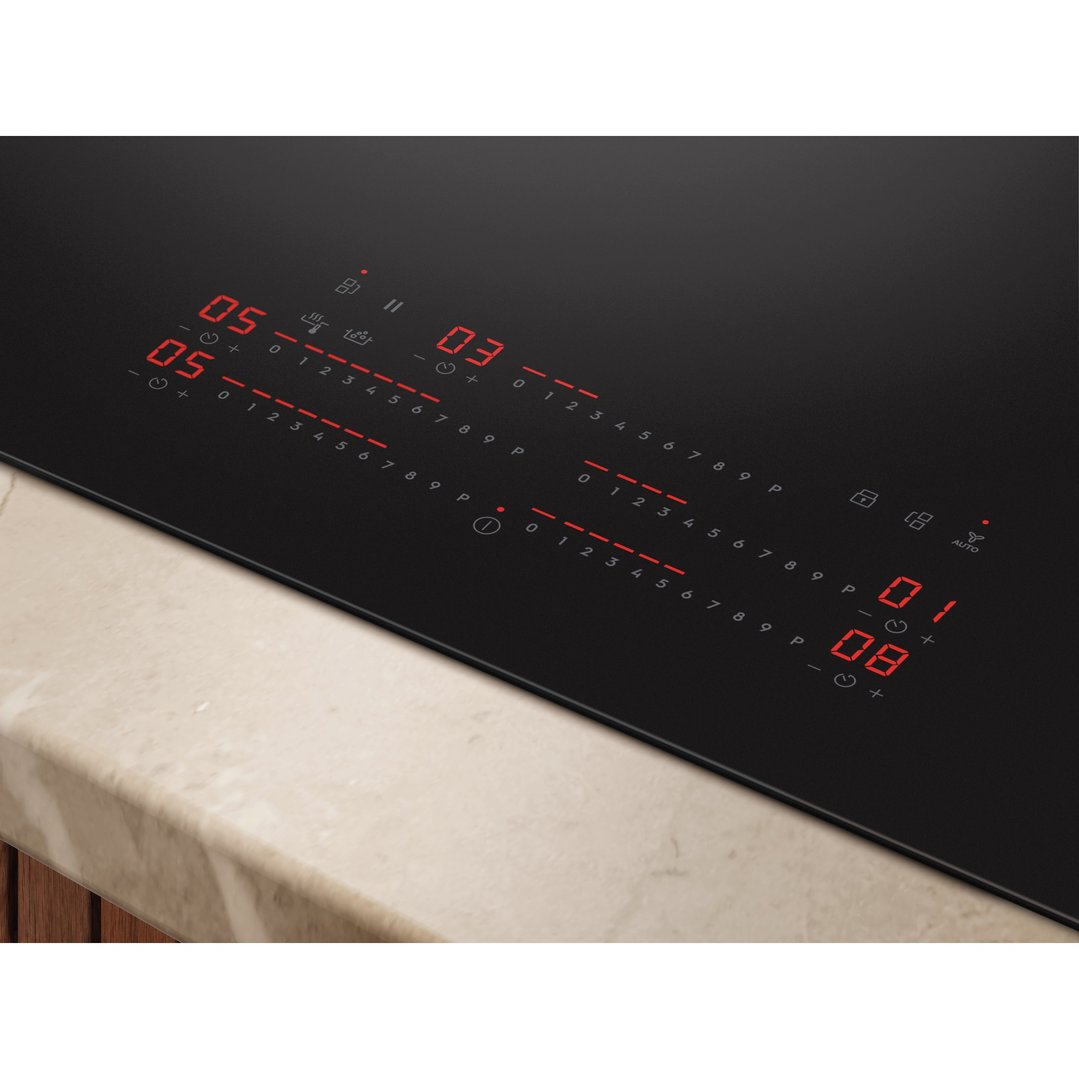 Close-up of an induction cooktop with red digital controls on a marble countertop