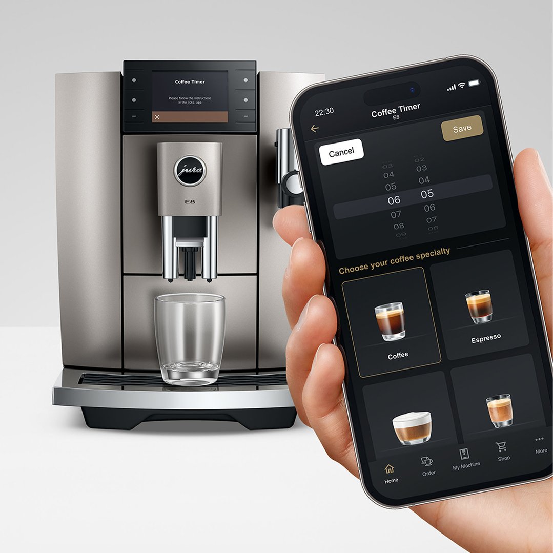 Hand holding a smartphone displaying coffee timer app next to a coffee machine