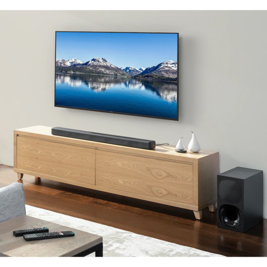 Soundbar and subwoofer in a living room with a TV and wooden media console