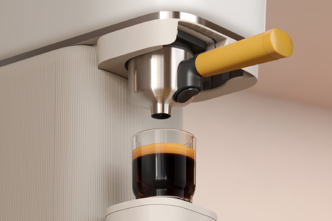 Coffee machine dispensing espresso into a glass cup with crema
