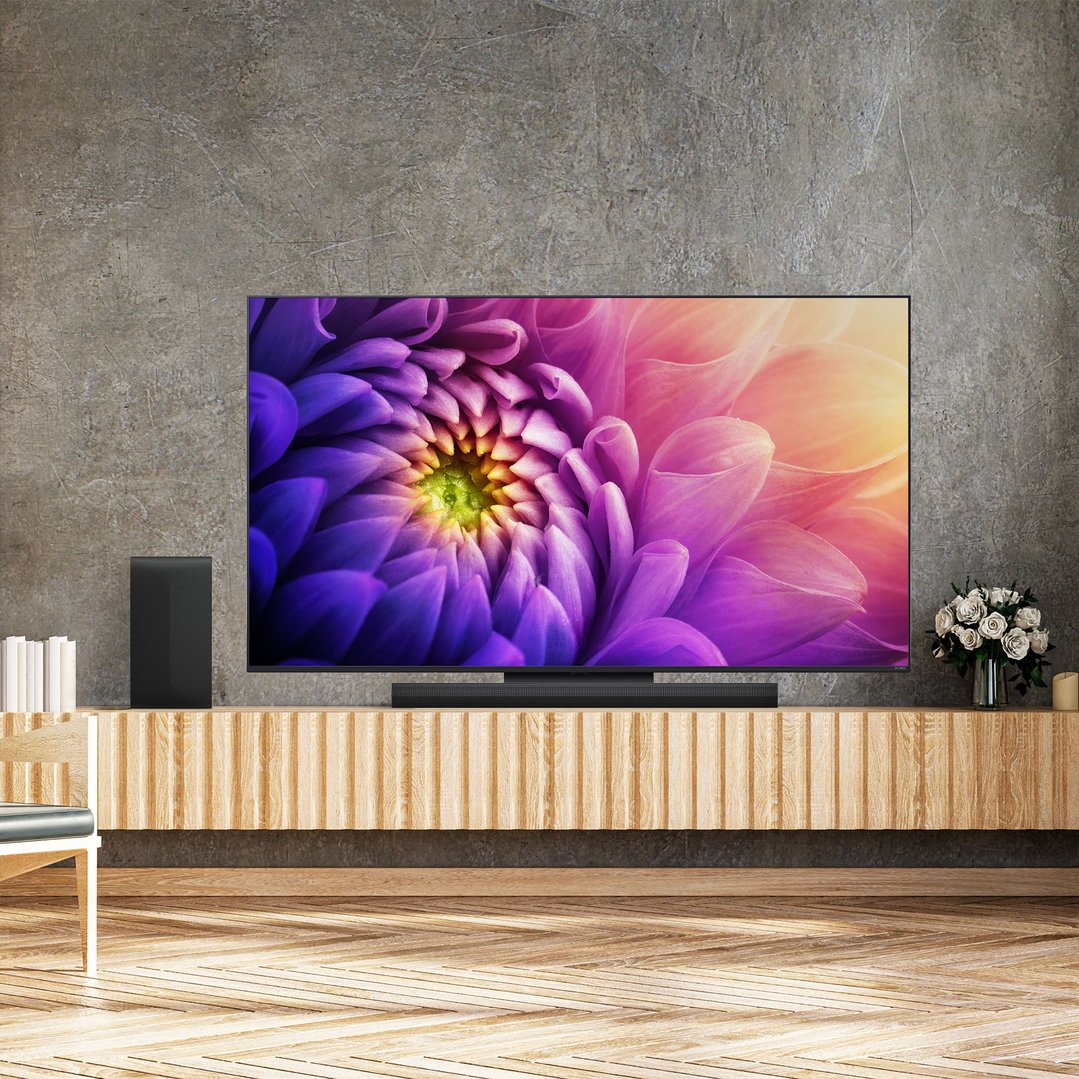 A sound bar and subwoofer on a wooden media console under a large TV