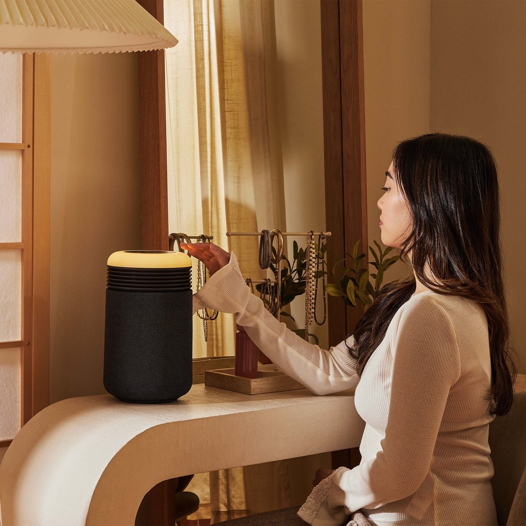 Woman interacting with an air purifier on a vanity table in a bedroom