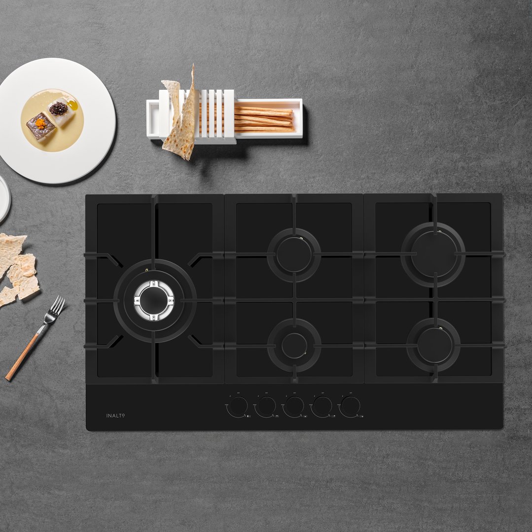Black InAlto gas on glass cooktop on a dark grey countertop with food