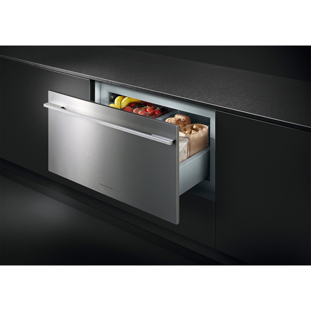 Integrated CoolDrawer multi-temperature drawer open with food in a dark kitchen
