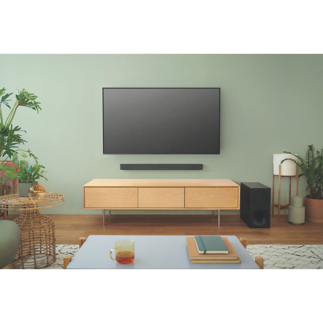 Soundbar and wireless subwoofer in a living room with a TV and wooden cabinet