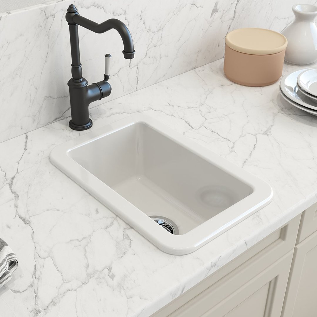 White fireclay sink with a black faucet on a marble countertop