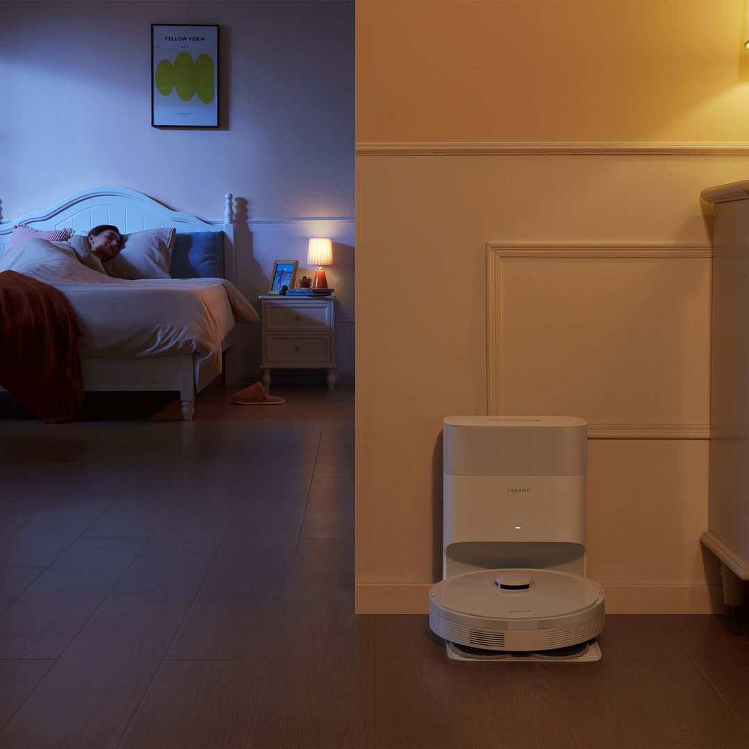 A DREAME robot vacuum cleaner and dock in a bedroom at night