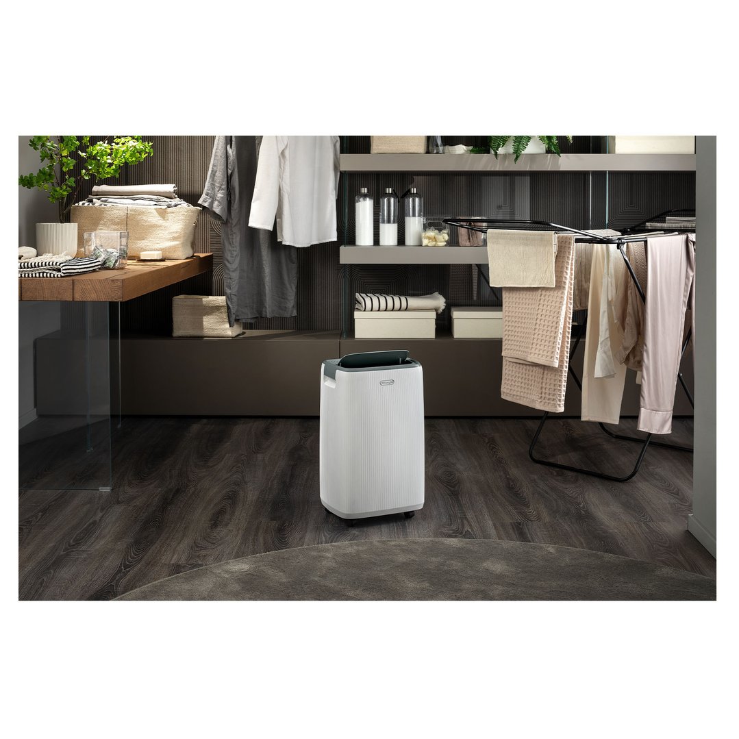 A De'Longhi dehumidifier in a laundry room with clothes drying on a rack