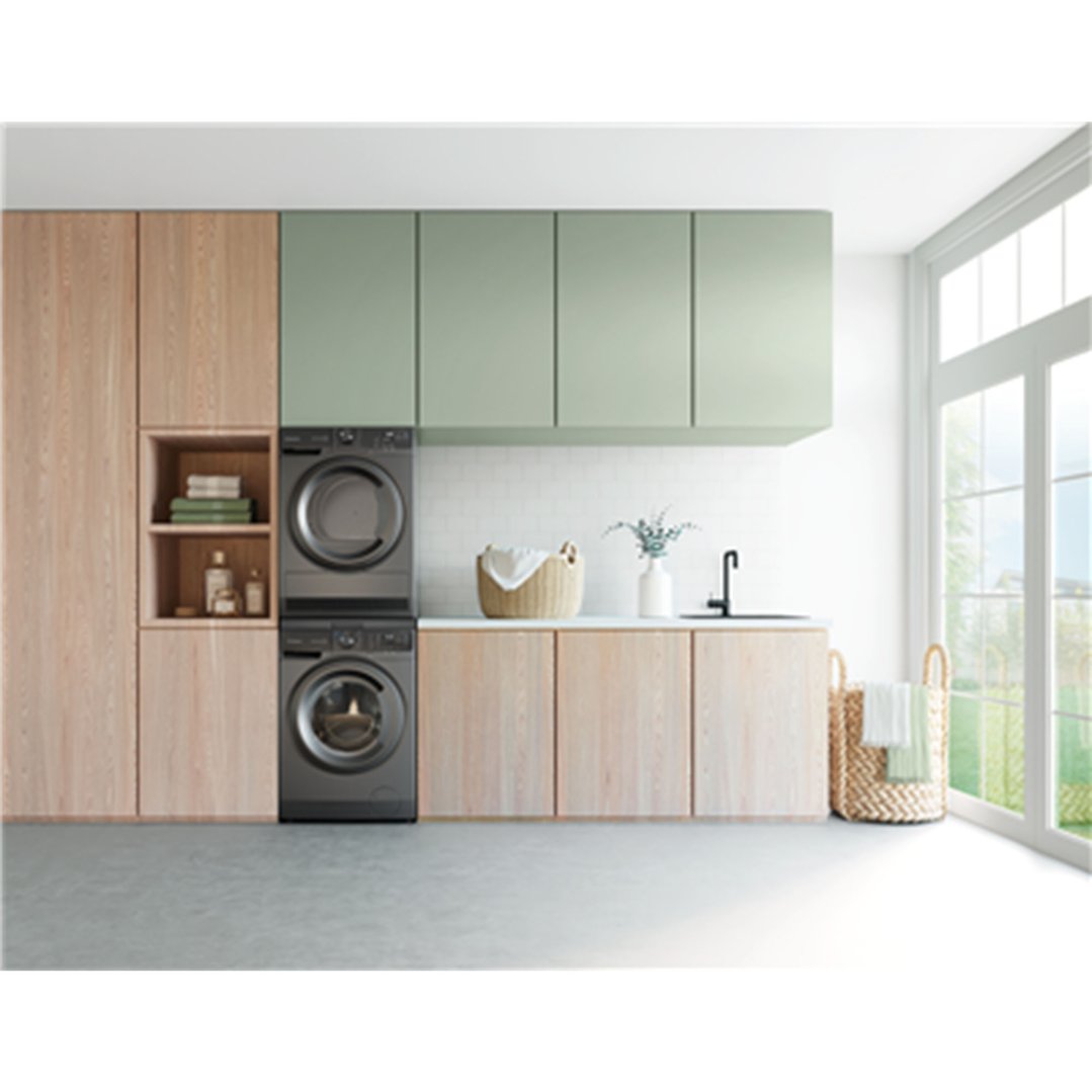 Dark washer and dryer stacked in a modern laundry room with light wood cabinets