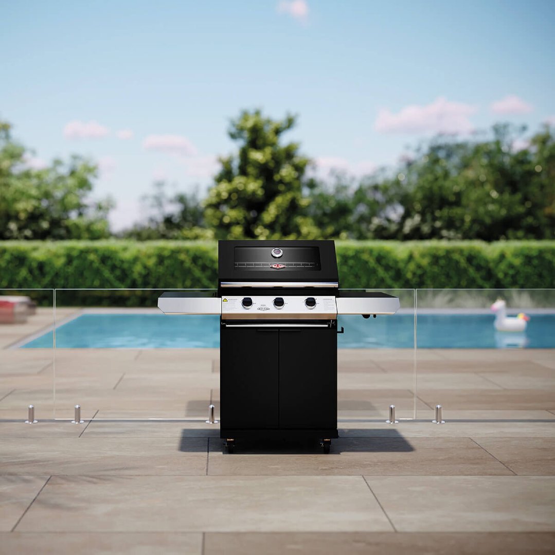 Black 3 burner barbecue on a patio next to a swimming pool