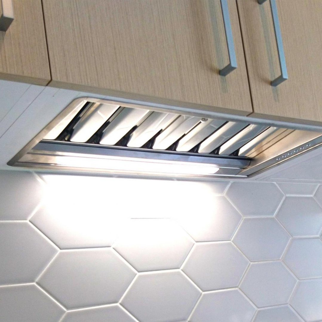 Undermount rangehood installed above a white hexagonal tiled backsplash
