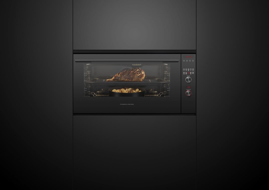 Built-in oven cooking a large roast and potatoes in a dark kitchen