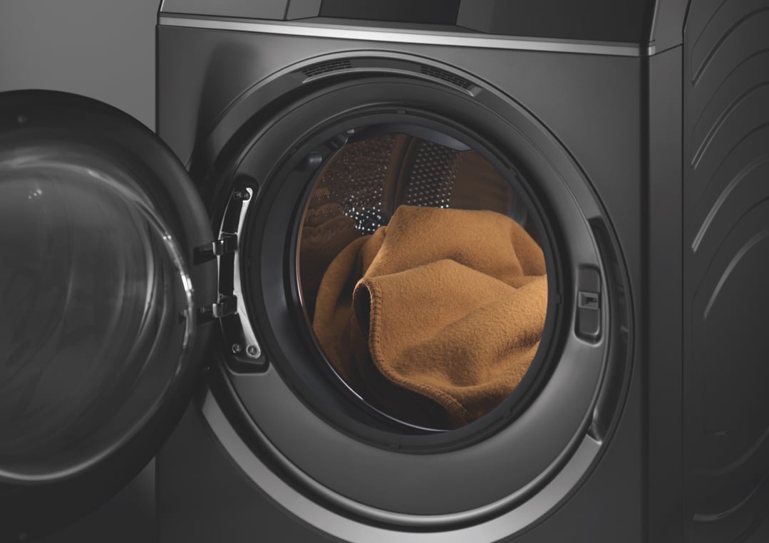 Close up of a dark washer dryer combo with a brown blanket inside