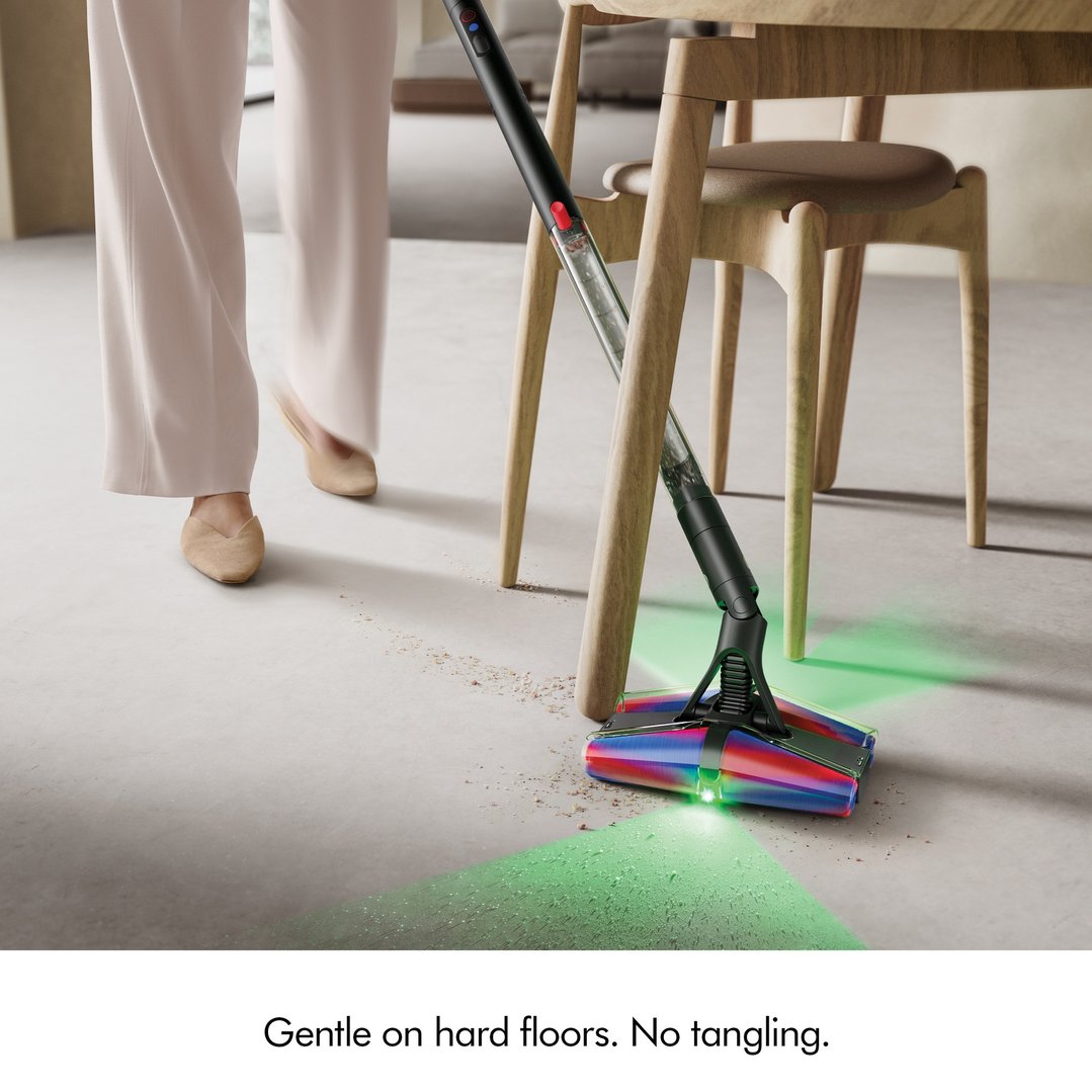 A person using a black handStickVacuum with illuminated head to clean a hard floor