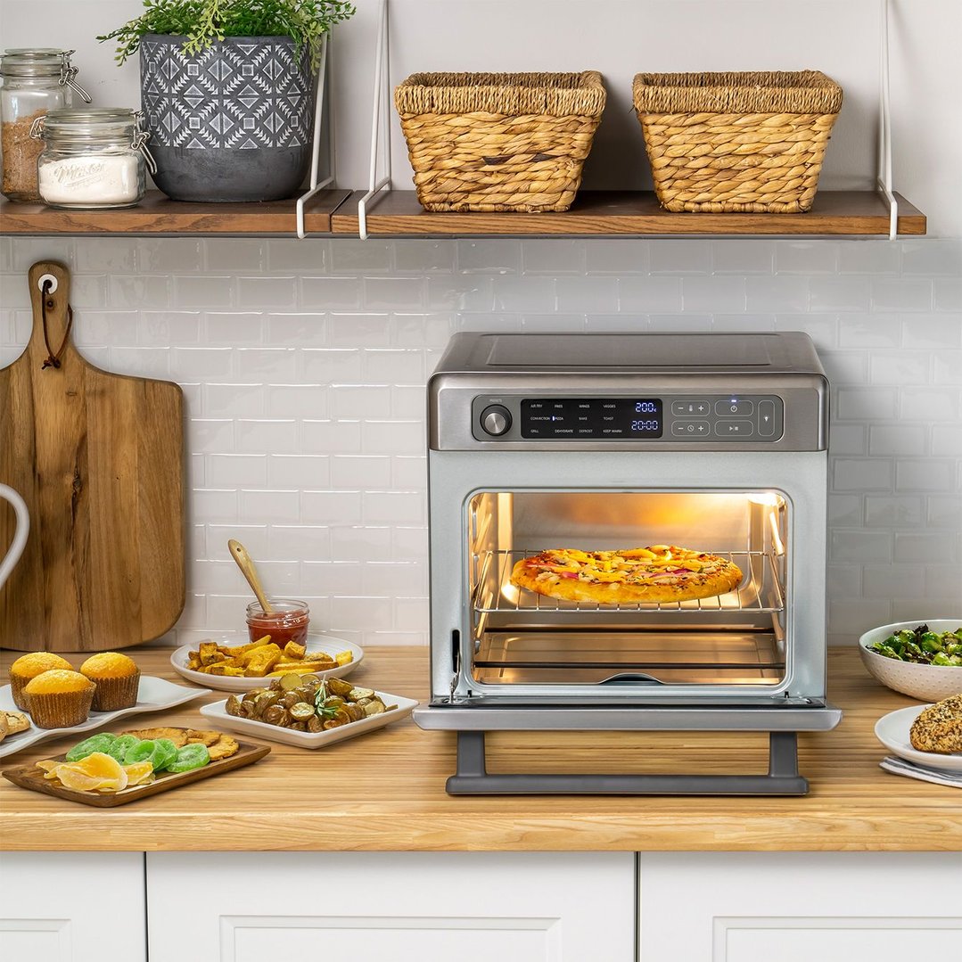 Digital multifunctional air fryer oven on a kitchen counter with various foods