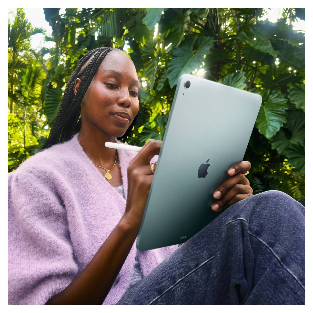 Woman in a purple cardigan using an Apple iPad Air with a stylus outdoors