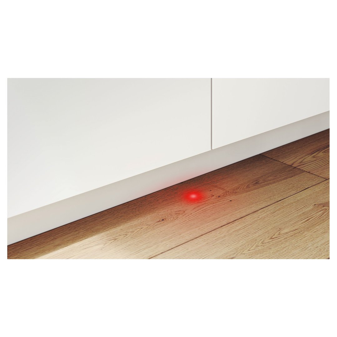 Red light from dishwasher shining on wooden floor in a kitchen