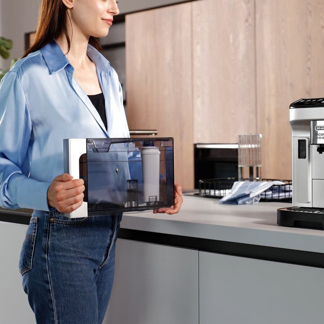 Woman holding a DELONGHI Water Impurity Filter in a modern kitchen setting