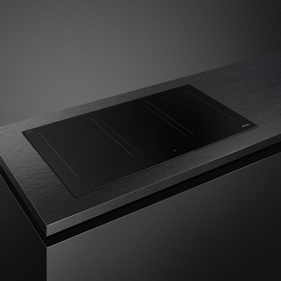 Black induction cooktop built into a dark countertop in a modern kitchen