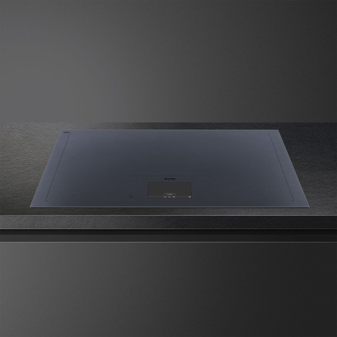 Dark grey induction cooktop with digital display built into a dark countertop