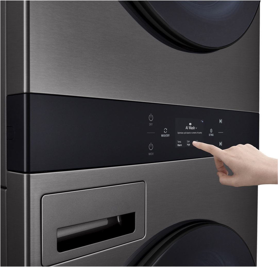 A hand touching the control panel of an LG AI WashTower™ washer dryer