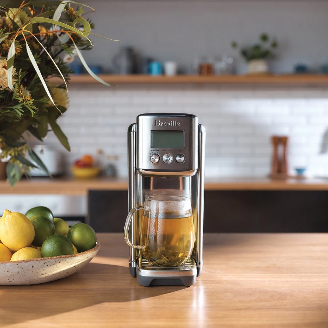 Breville AquaStation Hot Water Dispenser with tea in a glass mug on a wooden counter