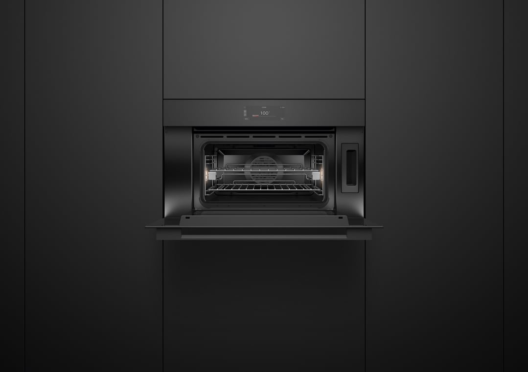Built-in black combi-steam oven with door open in a dark kitchen
