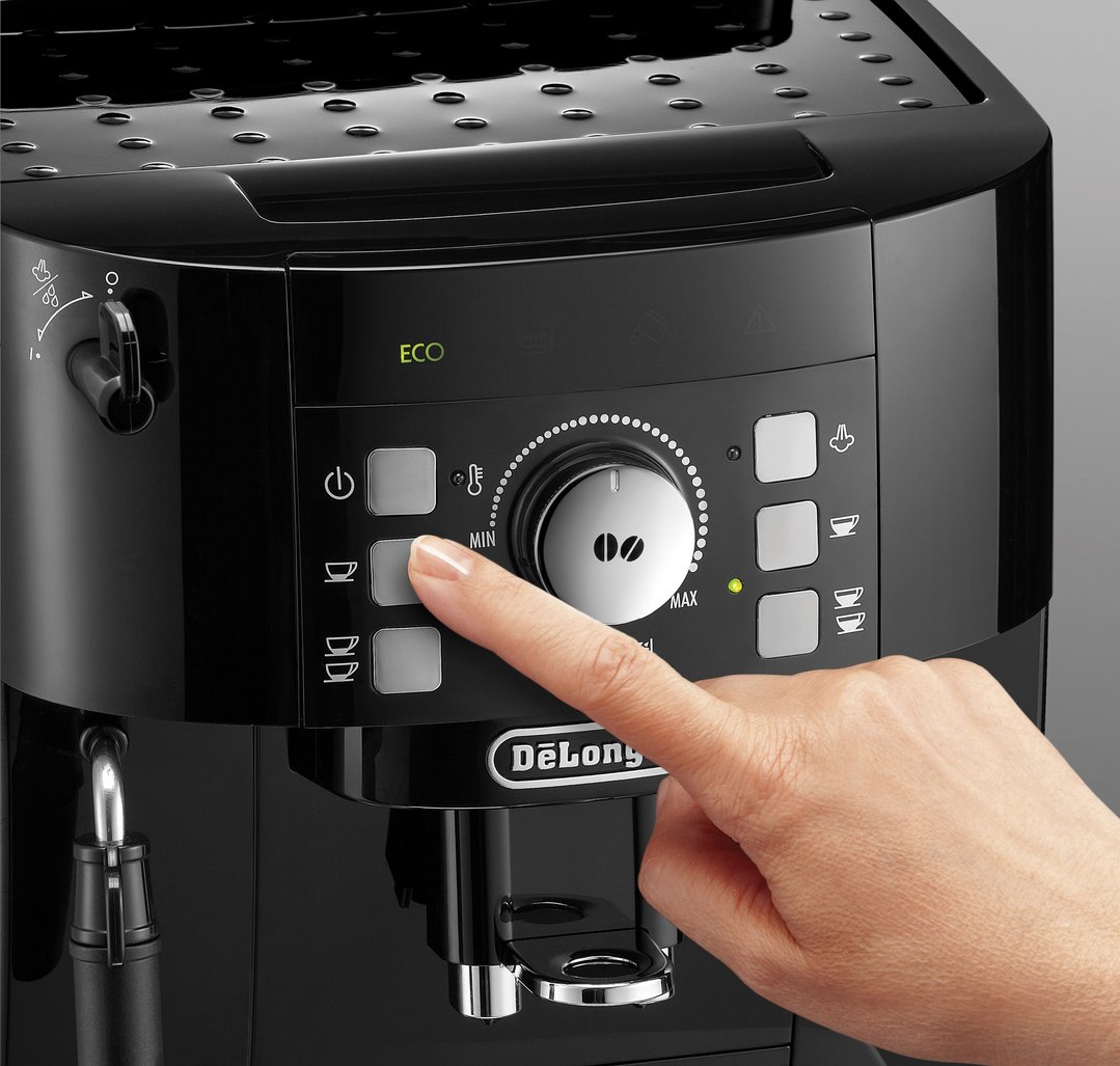 Hand pressing a button on the control panel of a black DELONGHI coffee machine