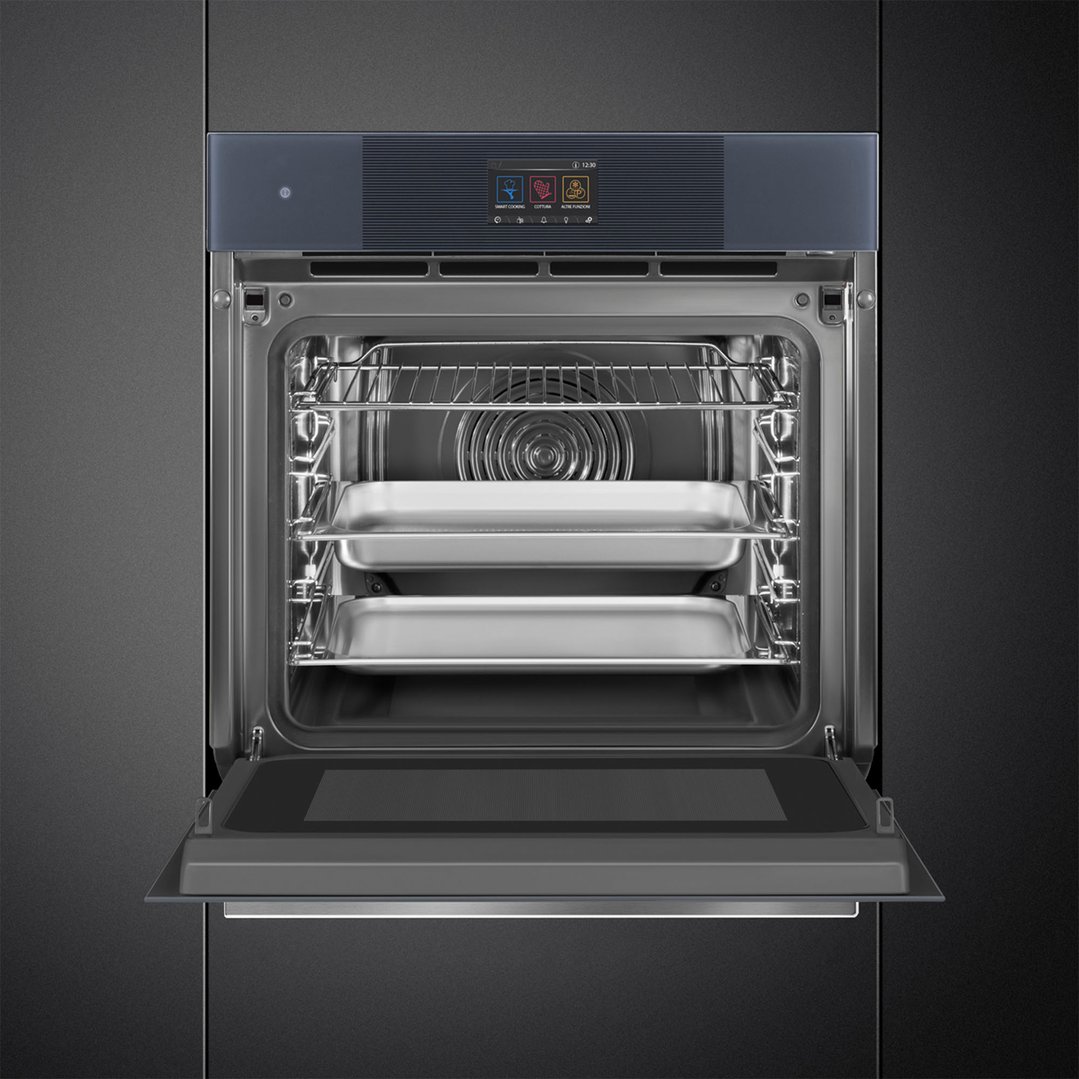 Open oven with two baking trays inside, built into a dark kitchen cabinet