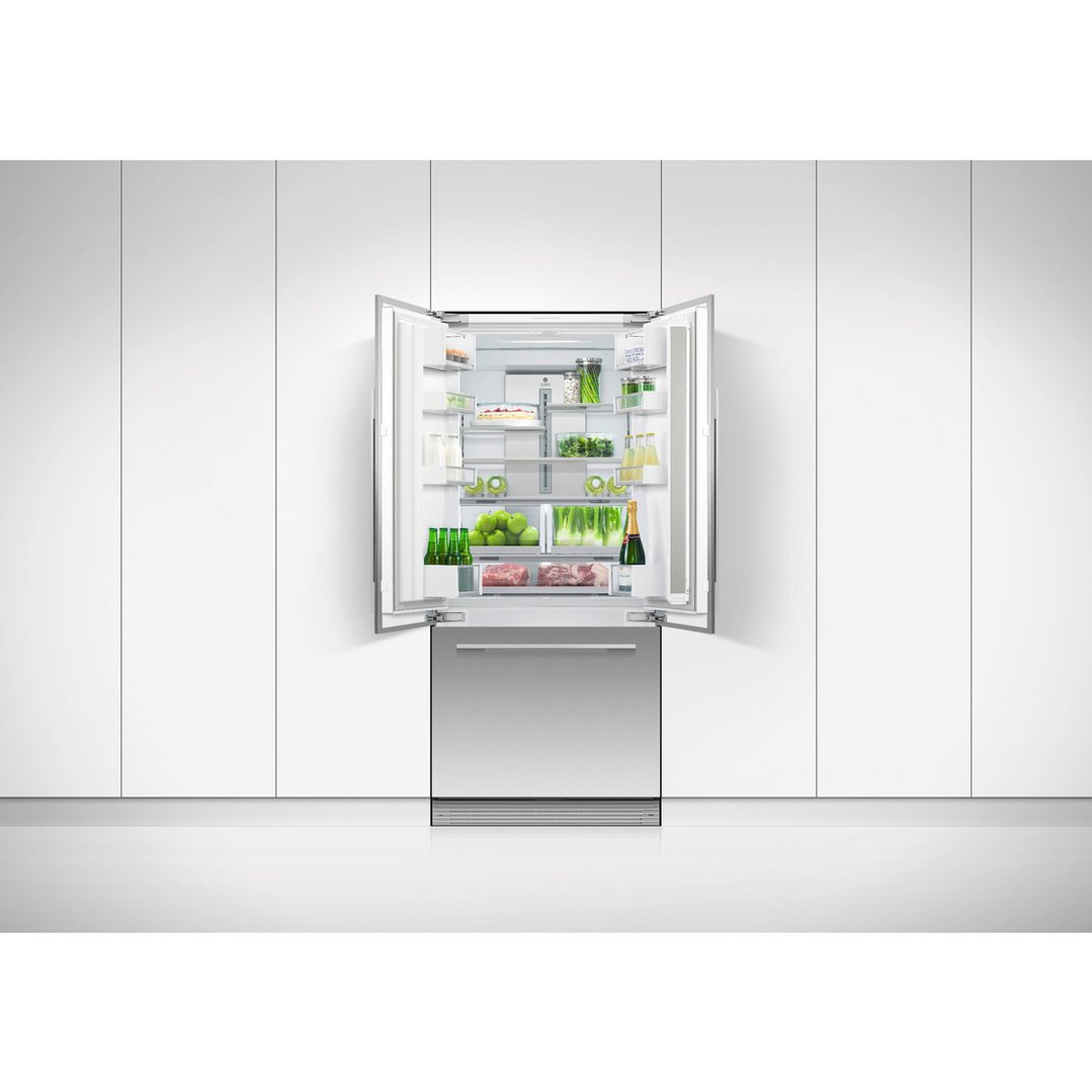 An open French door refrigerator freezer filled with food in a white kitchen