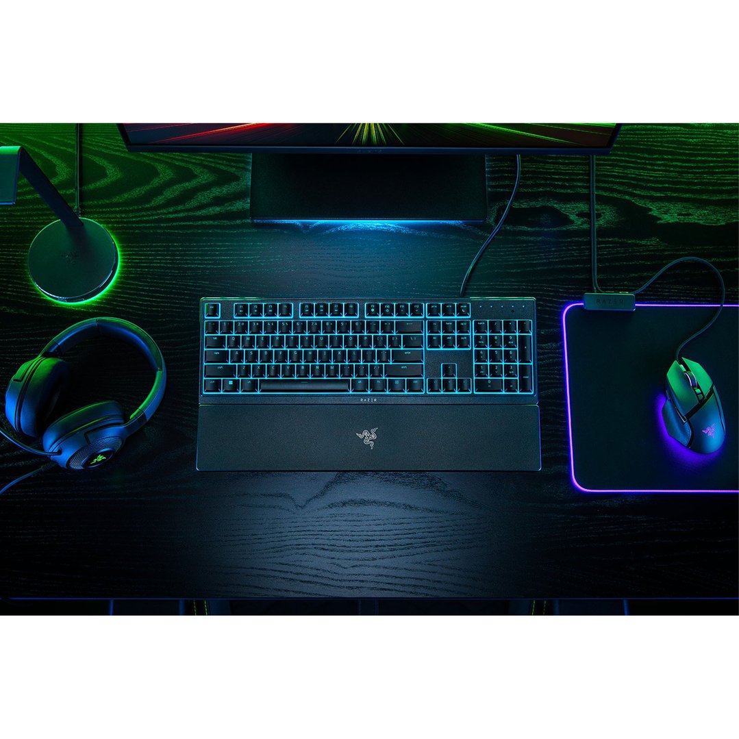 Razer gaming keyboard, mouse, and headphones on a dark wooden desk