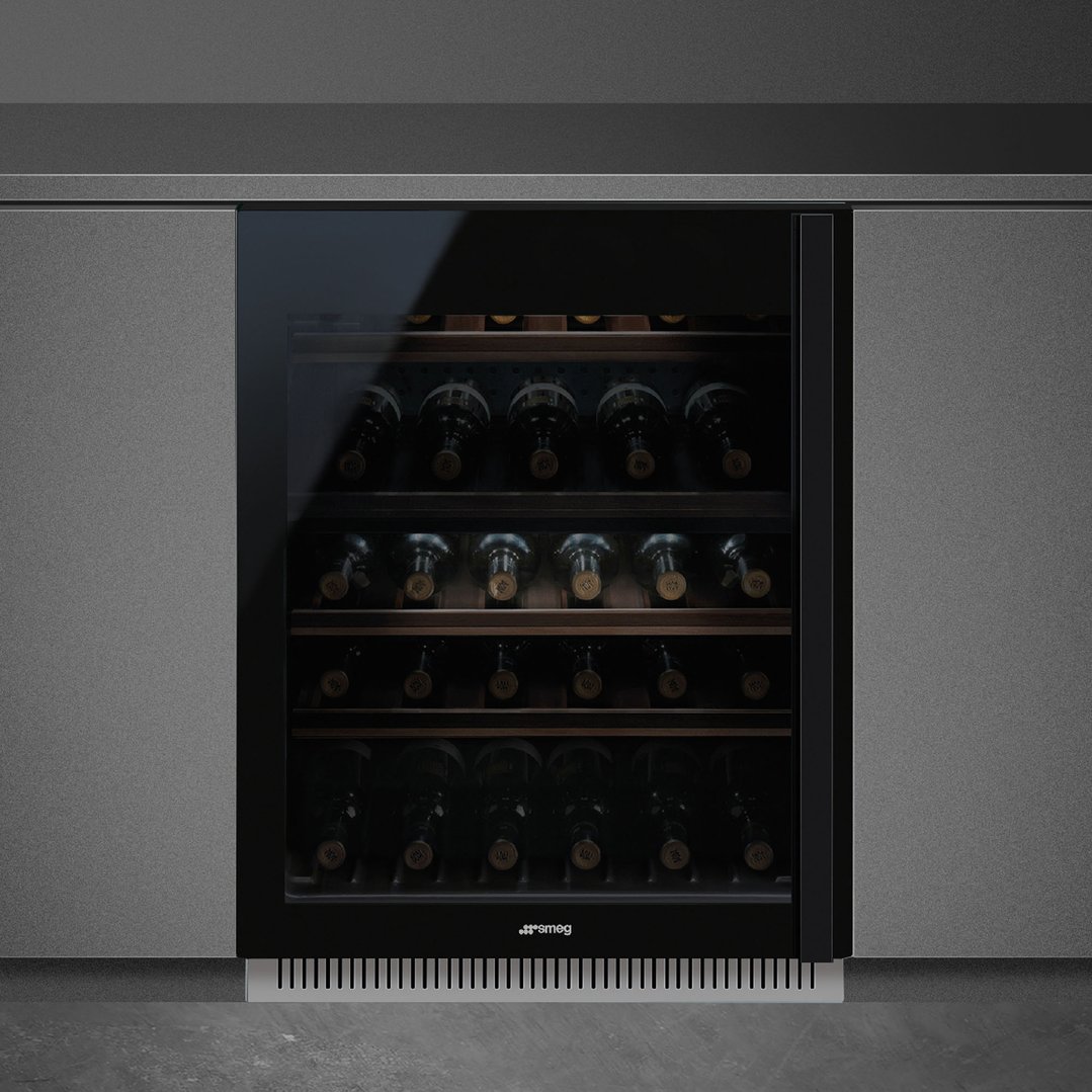 Built-in wine cooler with glass door displaying wine bottles in a dark kitchen