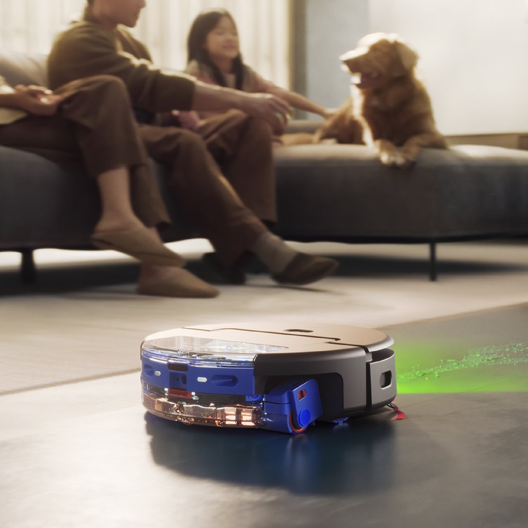 Dyson robot vacuum cleaner cleaning floor in a living room with people and dog